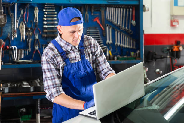 istock Male mechanic using laptop while repairing car in service 1321175400
