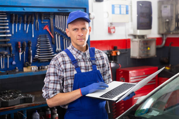 istock Male mechanic using laptop while repairing car in service 1321175463