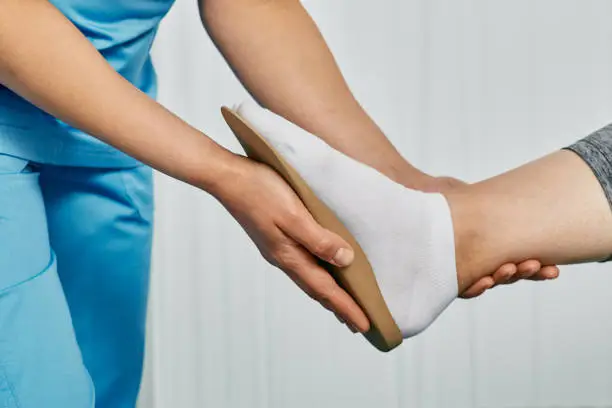 Photo of Orthopedic insoles. Orthopedist fitting individual orthopedic insole for patient foot