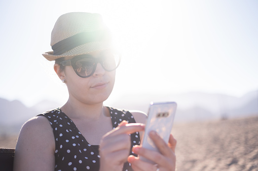 Young woman using smartphone on the beach.