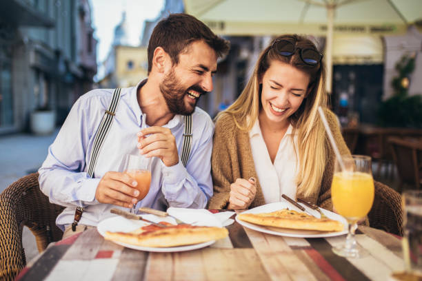 istock Young couple sitting in a restaurant eating pizza 1321178842
