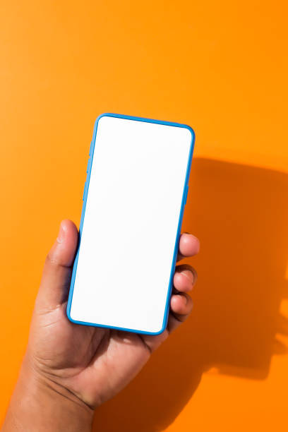 istock man hand holding blue smartphone with blank screen, isolated on orange background 1321178977