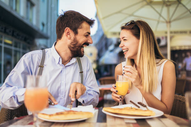 istock Young couple sitting in a restaurant eating pizza 1321179126
