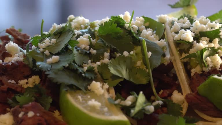 Side shot of some delicious looking street tacos filled with Carne Asada, Cilantro,  Cotija Cheese and Limes.