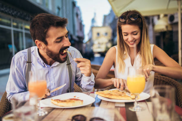 istock Young couple sitting in a restaurant eating pizza 1321180201