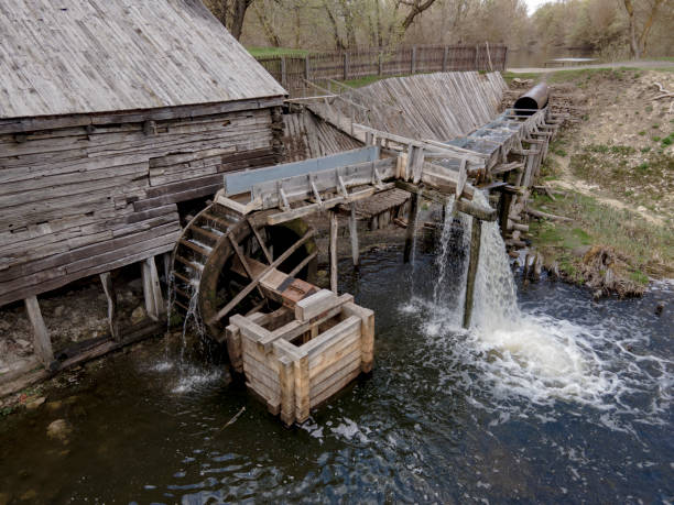 water mill wheel rotates under a stream of water. traditional village machinery - water wheel imagens e fotografias de stock