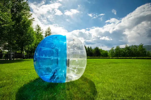 Photo of Zorbing Balloon on the summer lawn. inflatable zorb ball outdoor. Leisure activity concept with copy space