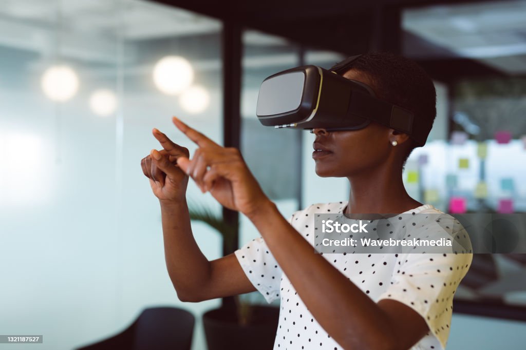Smiling african american woman using vr headset at work Smiling african american woman using vr headset at work. independent creative business at a modern office. Virtual Reality Simulator Stock Photo