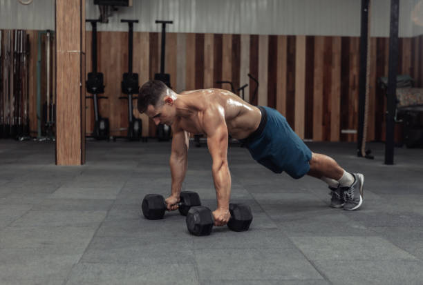istock Muscular powerful man doing push-ups with dumbbells in gym 1321188652