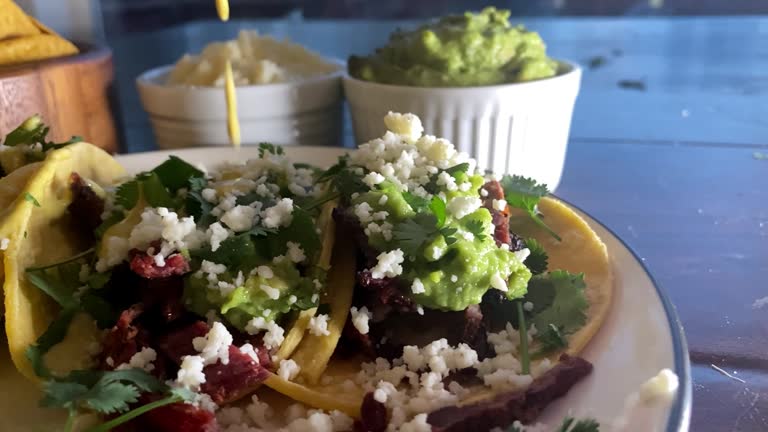 Side shot of some delicious looking street tacos filled with Carne Asada, Cilantro,  Cotija Cheese and Limes.