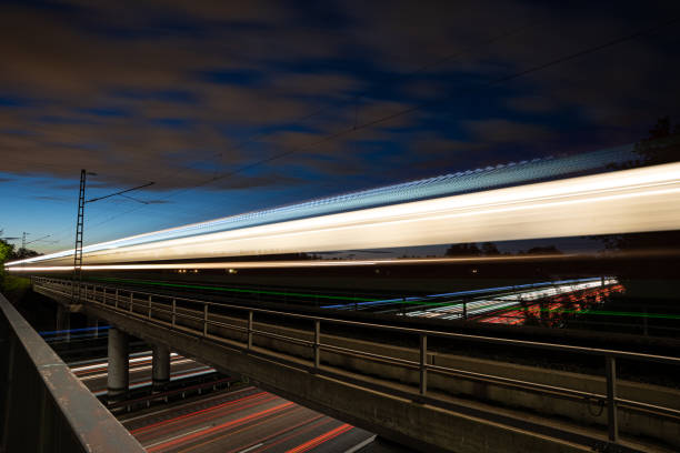 istock Light trails of a Train on a Bridge while under it there are light trails on the autobahn 1321190348
