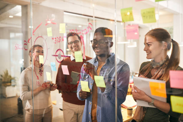 istock Happy black businessman and his colleagues working on creative ideas and making mind map on glass wall in the office. 1321190564