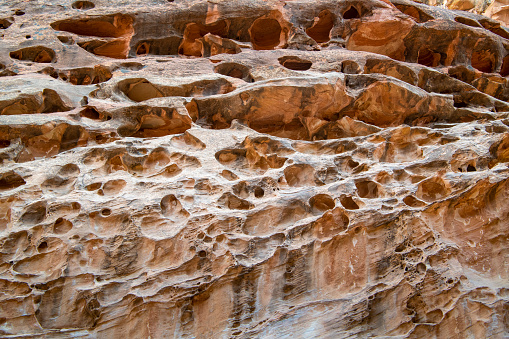 These pock-marked formations, usually found along sandstone washes and canyons, have been called “Swiss cheese” and other fanciful names, but are currently referred to by the more prosaic term “solution cavities”.  These examples are found in Capitol Reef National Park, Utah.