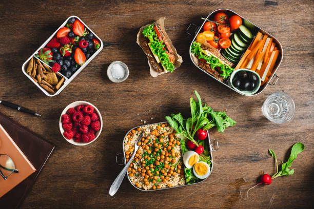 Healthy lunch in boxes Top view of a healthy meal prep containers on wooden table. Cooked food with salad, fruits and berries in lunch boxes. flat lay. Food in boxes for school or office. lunch box photos stock pictures, royalty-free photos & images