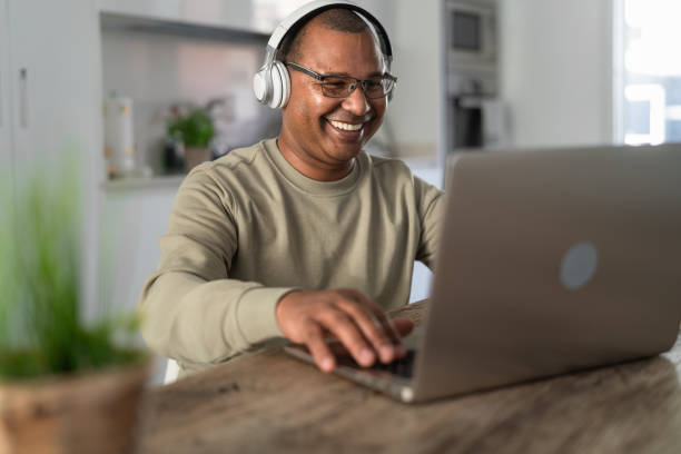 szczęśliwy starszy mężczyzna bawiąc się robiąc za pomocą laptopa w domu - technologia i inteligentna koncepcja pracy - working man audio zdjęcia i obrazy z banku zdjęć