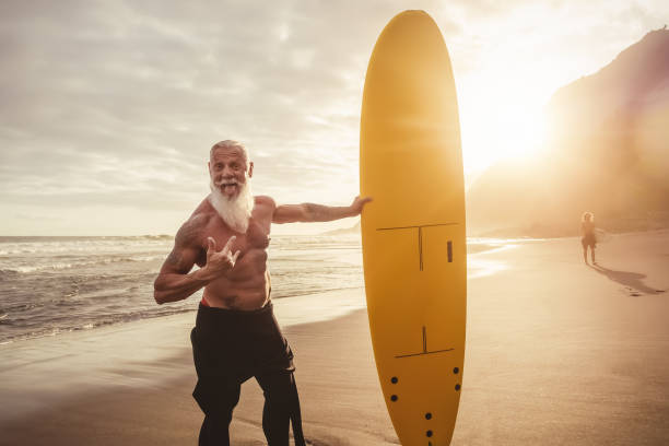 istock Fit senior male having fun surfing during sunset time - Retired man training with surfboard on the beach - Elderly healthy people lifestyle and extreme sport concept 1321196018