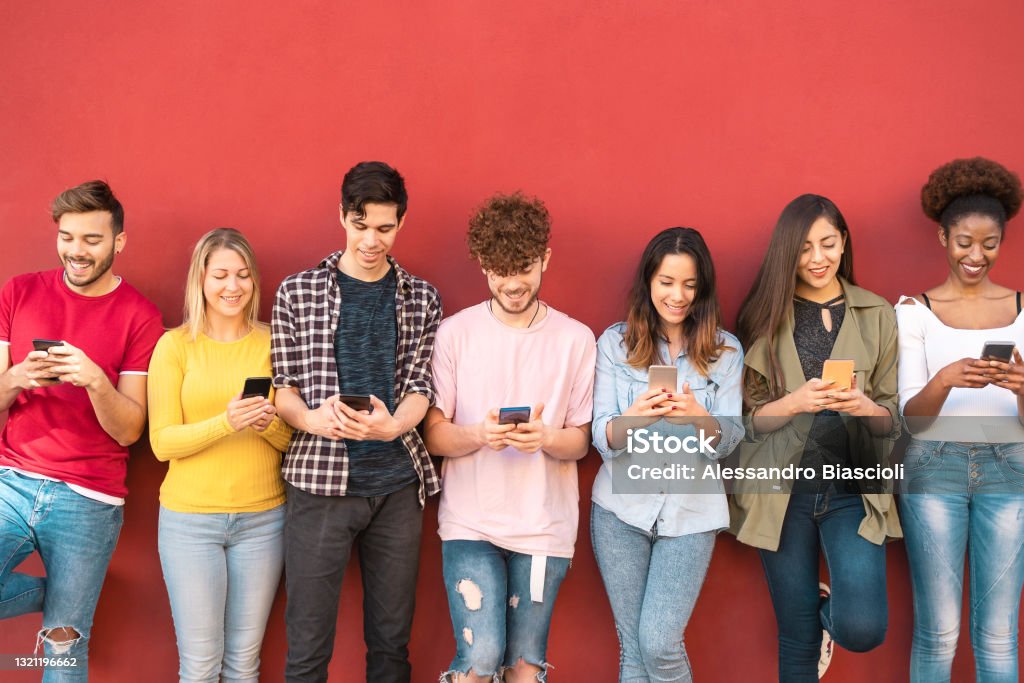 Group young friends using mobile smartphone outdoor - Millennial generation having fun with new trends social media apps - Youth technology people addicted - Red background Social Media Stock Photo