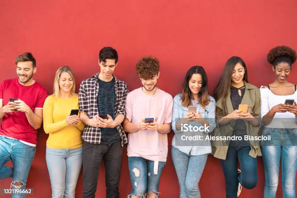 Group Young Friends Using Mobile Smartphone Outdoor Millennial Generation Having Fun With New Trends Social Media Apps Youth Technology People Addicted Red Background Stock Photo - Download Image Now