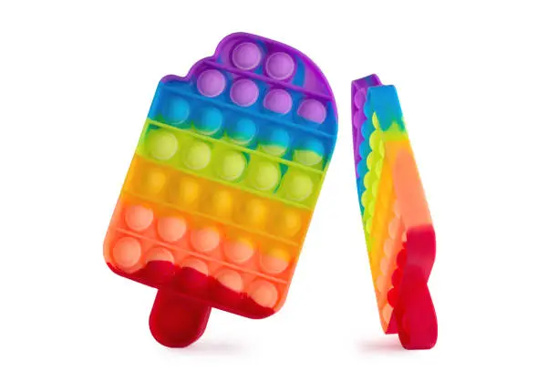 Photo of Pop it trendy kids fidget toy isolated on a white. Rainbow colored silicone sensory toy. Antistress gadget.