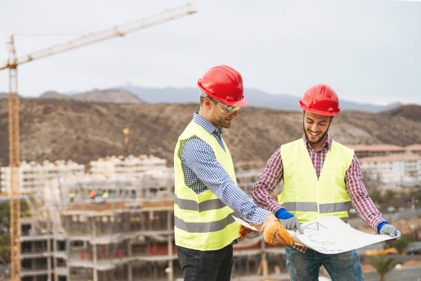 istock Work engineers discussing about new building area - Young builders reading the project in the construction site - Carpentry teamwork engineering concept 1321196786