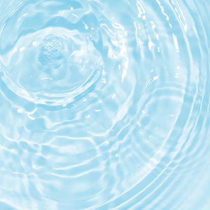 Surface of blue swimming pool. Texture of transparent blue water in swimming pool. Trendy abstract nature background. Water waves in sunlight with copy space