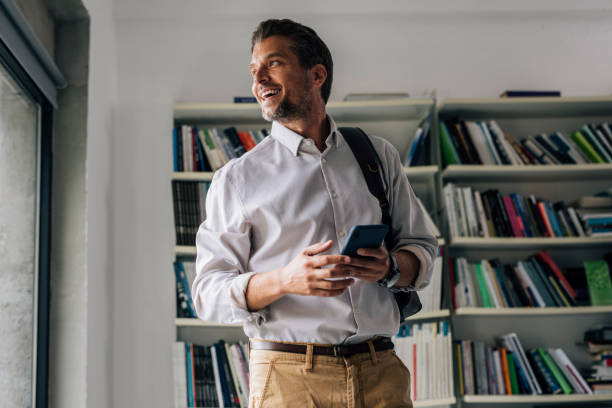 istock Handsome Businessman Standing in the Library and Using his Mobile Phone 1321204796