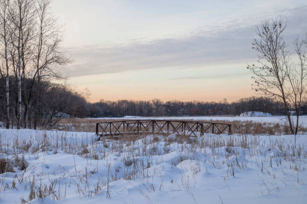 A Pedestrian Bridge in a Snowy Landscape during a Winter Sunset