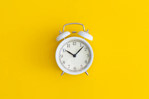istock White antique alarm clock on yellow background. Flat lay composition. Top view. 1321207669