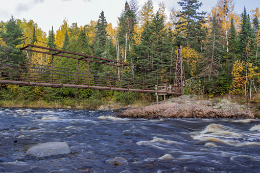 A Medium Landscape Shot of a Suspension Walking Bridge over the Rushing Baptism River in Northern Minnesota during a Beautiful Fall Day