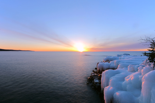 A Wide Angle View of a Golden Winter Sunrise Casting Warm Light on Icy Boulders on Lake Superior's North Shore in Minnesota Near Grand Marais