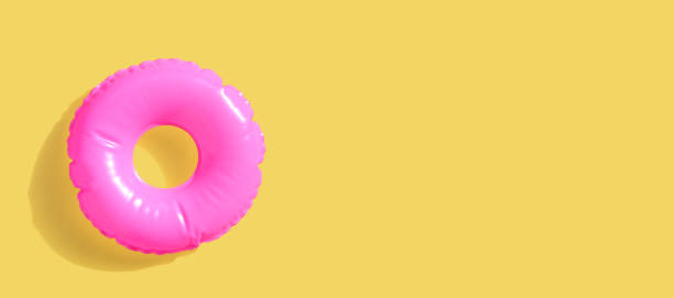 istock Pink inflatable swimming pool ring on yellow surface 1321209086