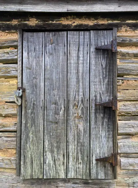 A weathered wooden door with lock and rusted hinges.