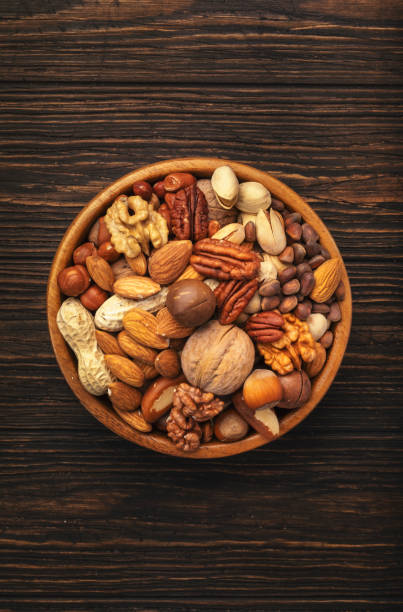 istock Nuts in bowls. Walnuts, pistachios, pecans, macadamia, almonds and other. Healthy food snacks mix on wooden background, top view 1321221406