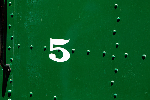 The number five painted on the side of an old train.
