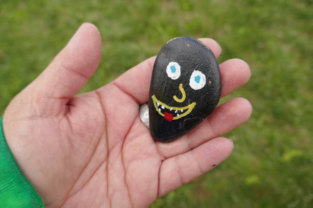 istock Silly funny face painted on kindness rock held in woman's hand 1321228227