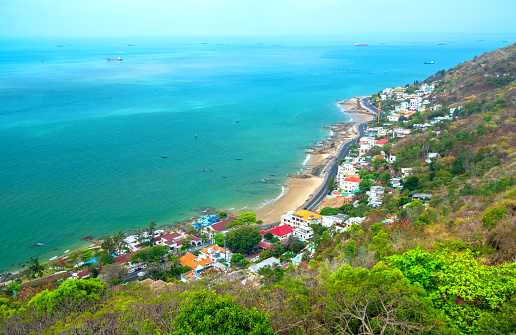 Aerial view on Vung Tau, Vietnam which is the popular beach city. There are crowded small building close to the sea and mountain.