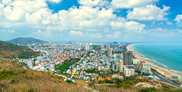 Aerial view on Vung Tau, Vietnam which is the popular beach city. There are crowded small building close to the sea and mountain.