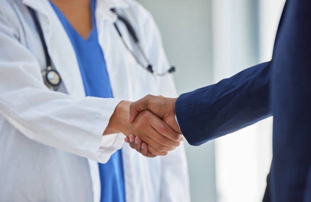 cropped shot of a doctor shaking hands with a businessman in a hospital - zoom victory imagens e fotografias de stock