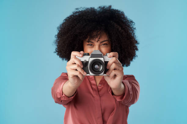 istock Studio shot of a young woman using a camera against a blue background 1321243449
