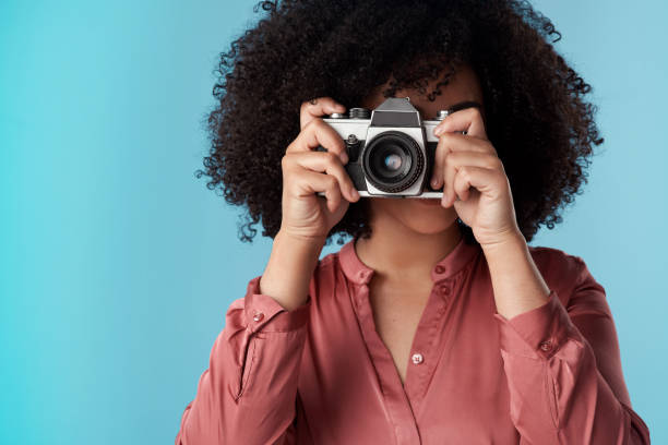 istock Studio shot of a young woman using a camera against a blue background 1321243451