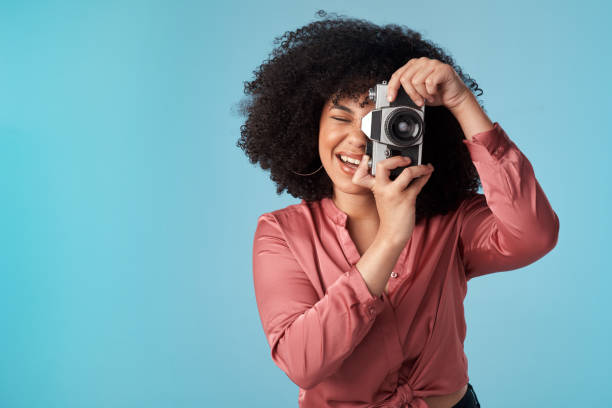 istock Studio shot of a young woman using a camera against a blue background 1321243452