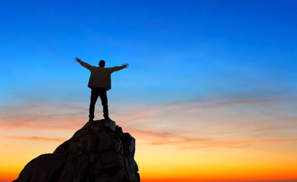 istock Cheering man with open arms on mountain peak cliff 1321243455