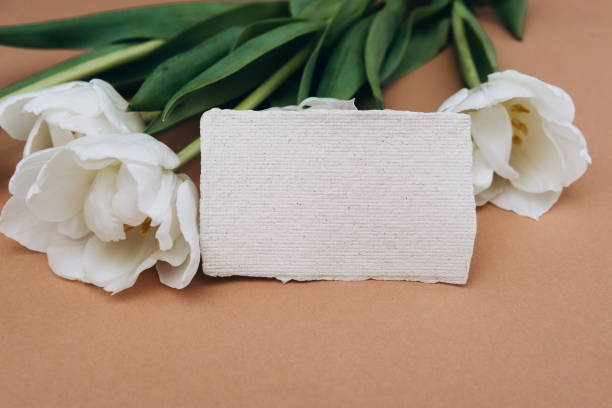 istock Blank card mockup on brown background with white tulips flowers. 1321244528