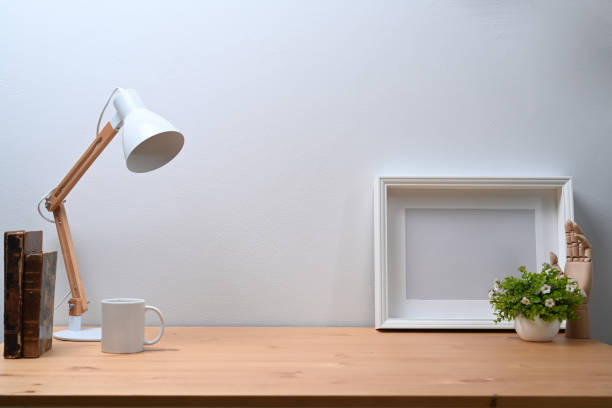istock Empty picture frame, houseplant, lamp and book on wooden table. 1321248914