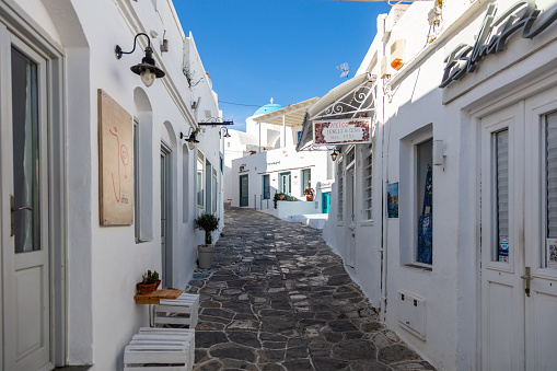 Greece, Sifnos island. May 19, 2021. Traditional greek architecture whitewashed buildings and narrow cobblestone streets, sunny day, clear blue sky. Closed shops, empty streets, coronavirus days.