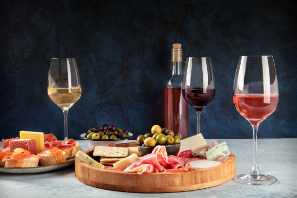 Wine and charcuterie and cheese board with a place for text Wine and charcuterie and cheese board with a place for text. Prosciutto di parma ham, blue cheese, olives and salmon sandwiches, Italian antipasti or Spanish tapas, a side view with copy space charcuterie stock pictures, royalty-free photos & images