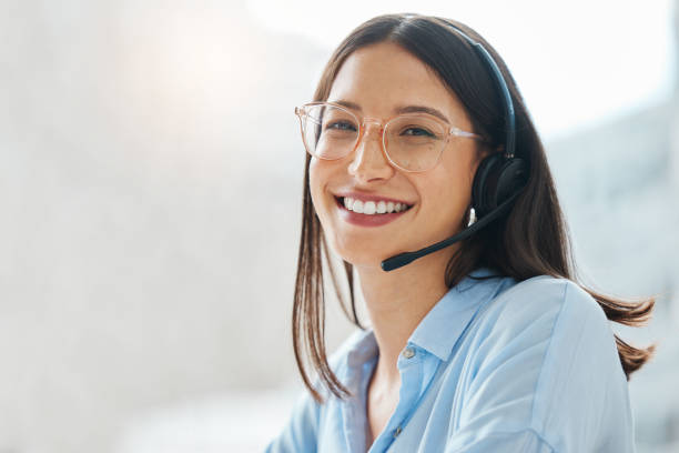 Shot of an attractive young saleswoman sitting alone in the office and wearing a headset Leave the hard work to me service stock pictures, royalty-free photos & images