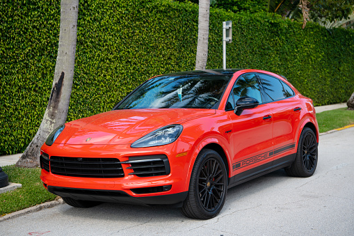 Palm Beach, Florida USA - March 21, 2021: orange Porsche Cayenne Coupe luxury car parked in palm beach, united states of america. front side view. Porsche is luxury car brand
