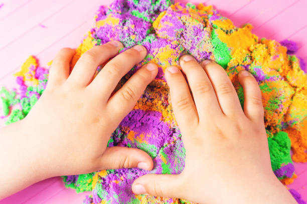 mains d’un enfant jouant avec du sable cinétique multicolore - sandbox child human hand sand photos et images de collection