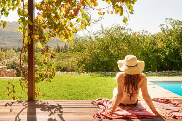 istock Woman in a bikini relaxing outdoors by a swimming pool 1321259745